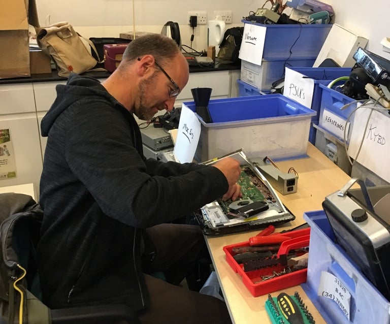 A Tech-Takeback technician works on a donated laptop