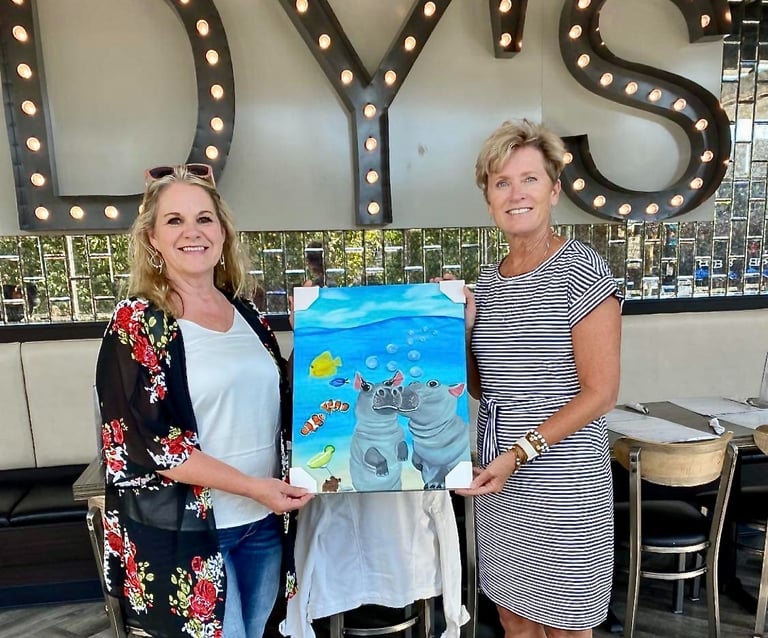 a woman holding a painting of a hippo