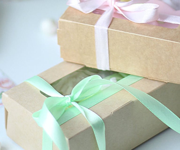 Handmade gift boxes in brown kraft paper with pastel pink and mint green ribbons.