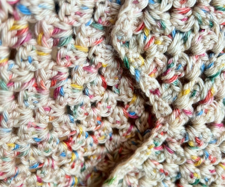 a close up of a crochet blanket with multicolored yarn