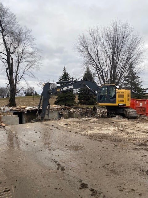 John Deere excavator digging up home from demolition project