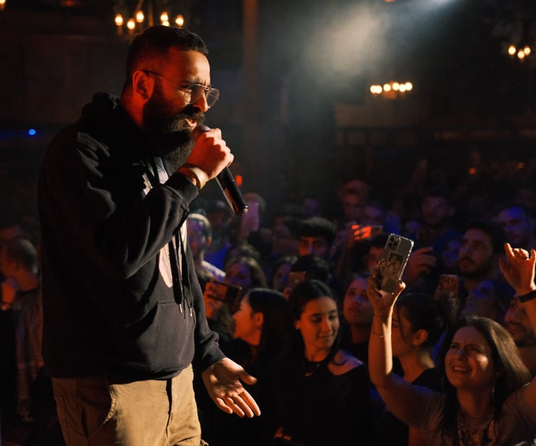 a man in a black jacket and sunglasses is holding a microphone in a concert rap performance