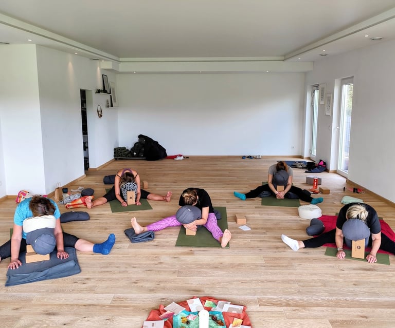 Yin-Yogastunde; Teilnehmende in Libellen-Pose