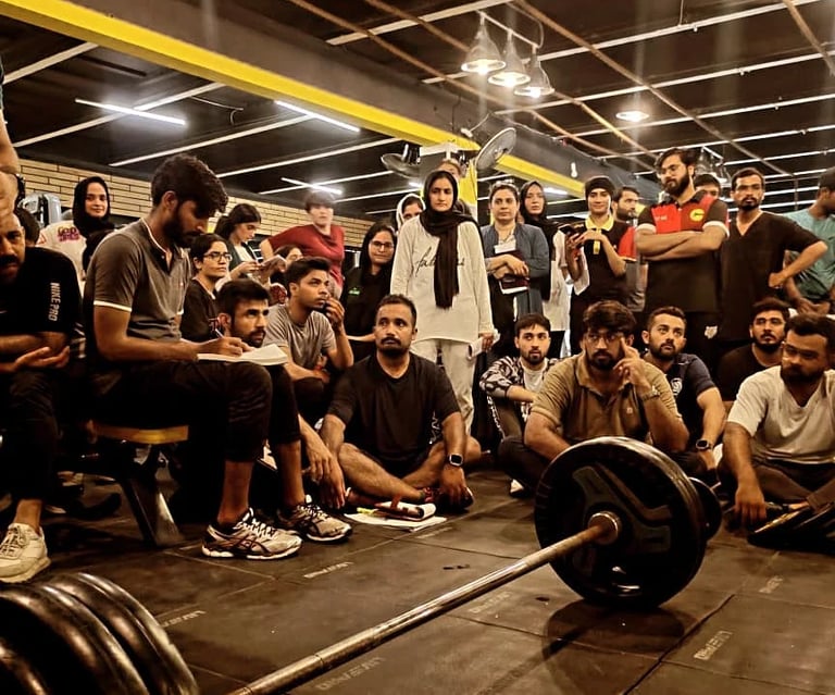A diverse group of athletes attending a fitness seminar and barbell training workshop in a gym setting.