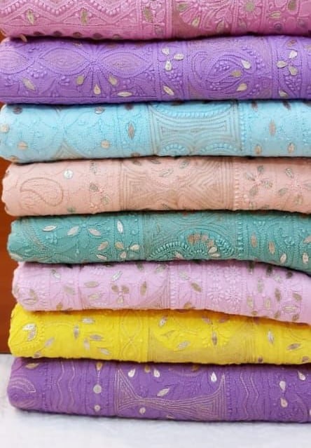 Stack of colorful Chikankari embroidered fabrics with sequins in pastel pink, blue, and yellow.
