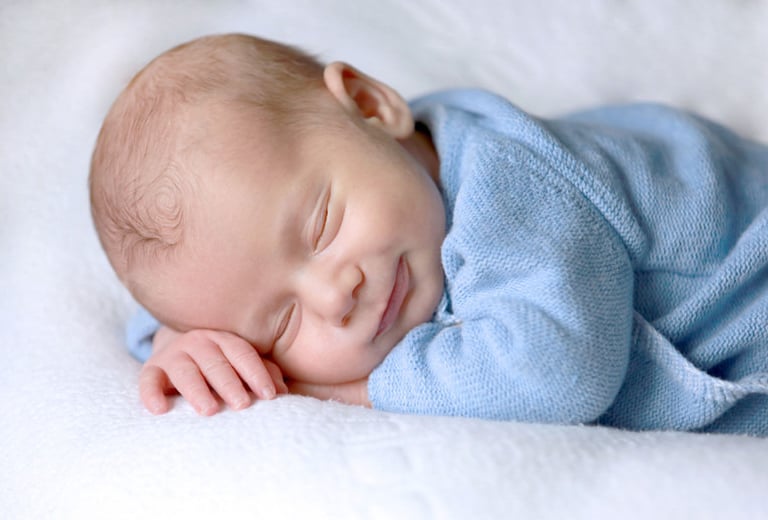 a happy baby sleeps on a blanket in a bed