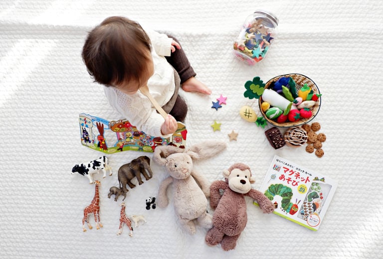 a little girl sitting on a blanket with toys