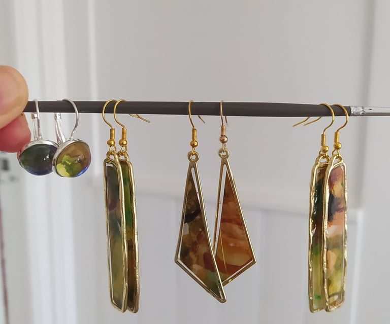 a person holding a pair of earrings with a picture of a woman's hand