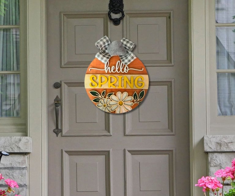 A welcoming door hanger that says "Hello Spring" hanging on a house door