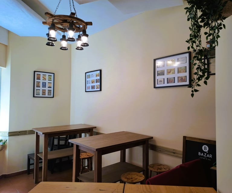 Zona interior del Bar Las Tinajas Huelva, con mesas altas, cuadros en la pared, lámpara colgante y planta decorativa.