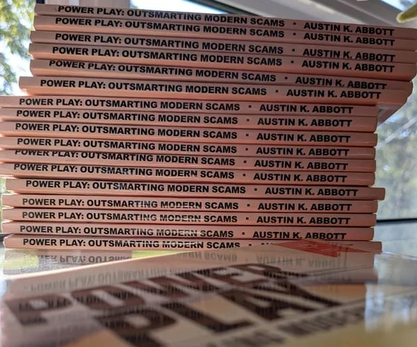 Stack of books titled Power Play: Outsmarting Modern Scams by Austin K. Abbott, arranged with their spines facing outward