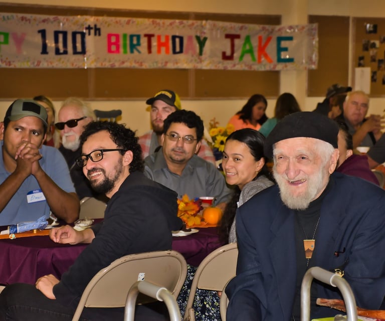 a group of people smiling and sitting at a table with food
