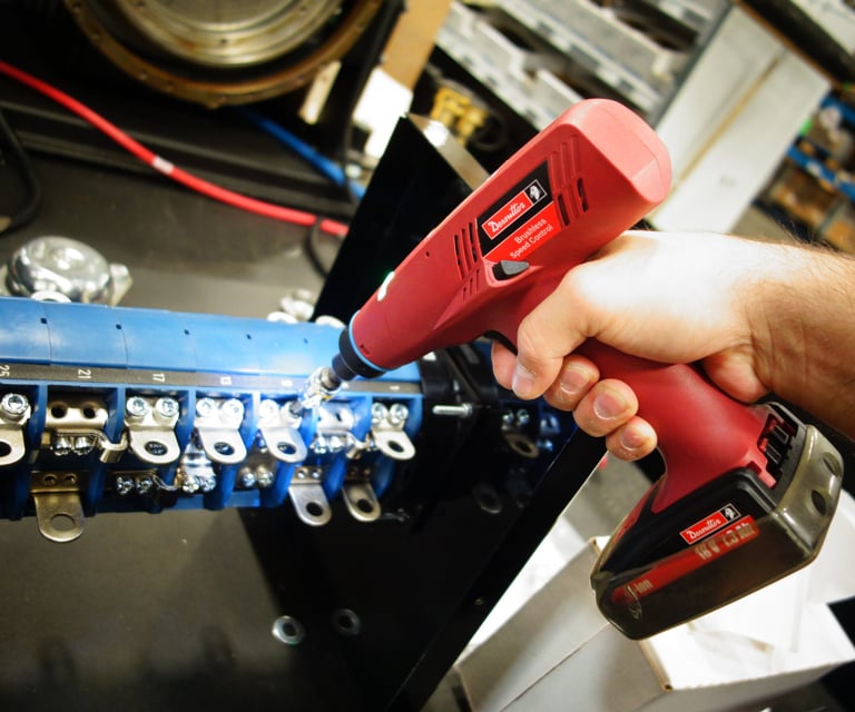 A technician uses a Desoutter cordless electric nutrunner to assemble an industrial electrical component.