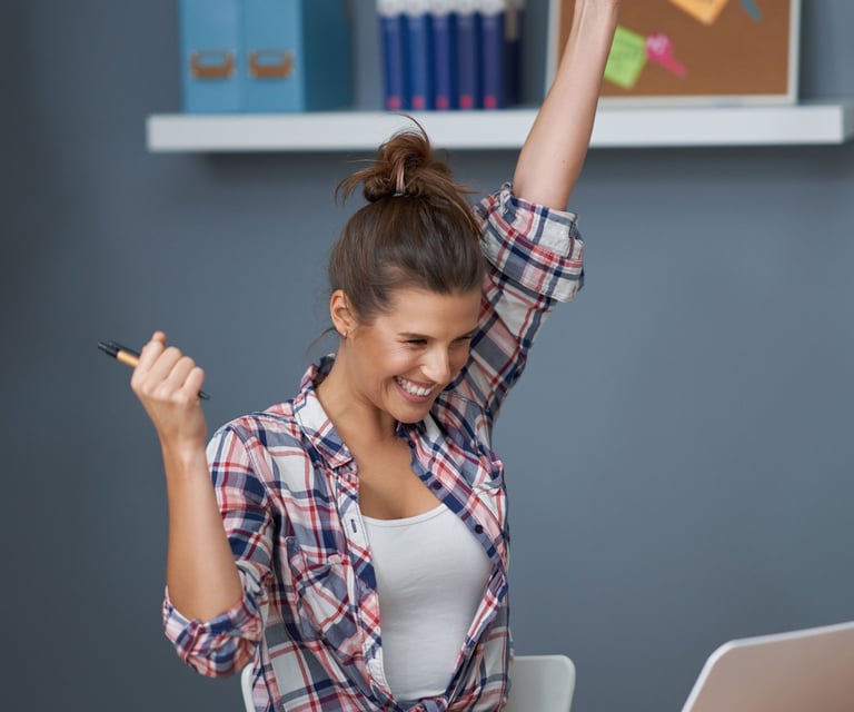 a woman sitting at a desk with her arms up in the air
