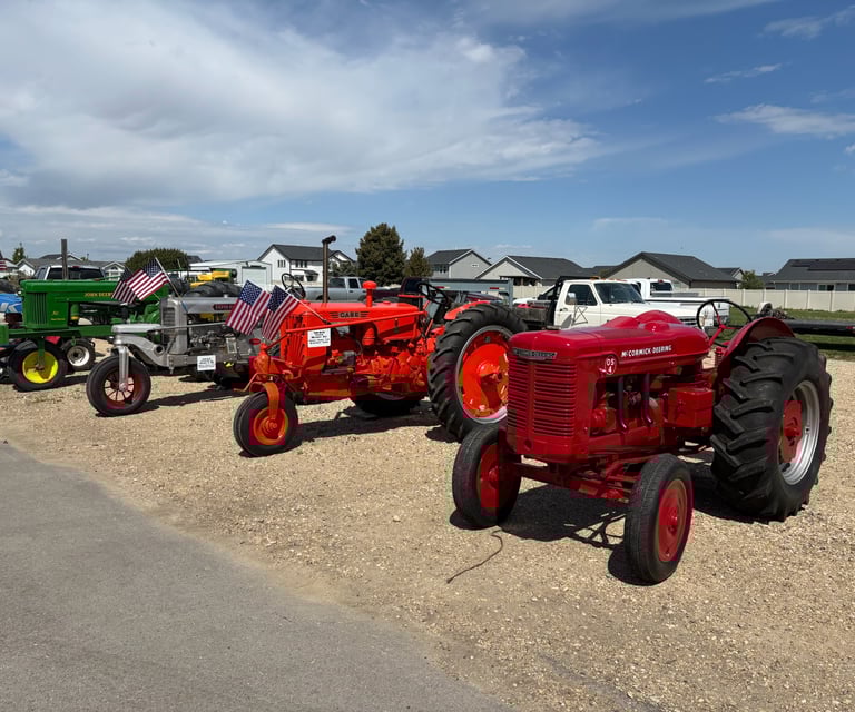 a row of tractors parked in a gravel lot