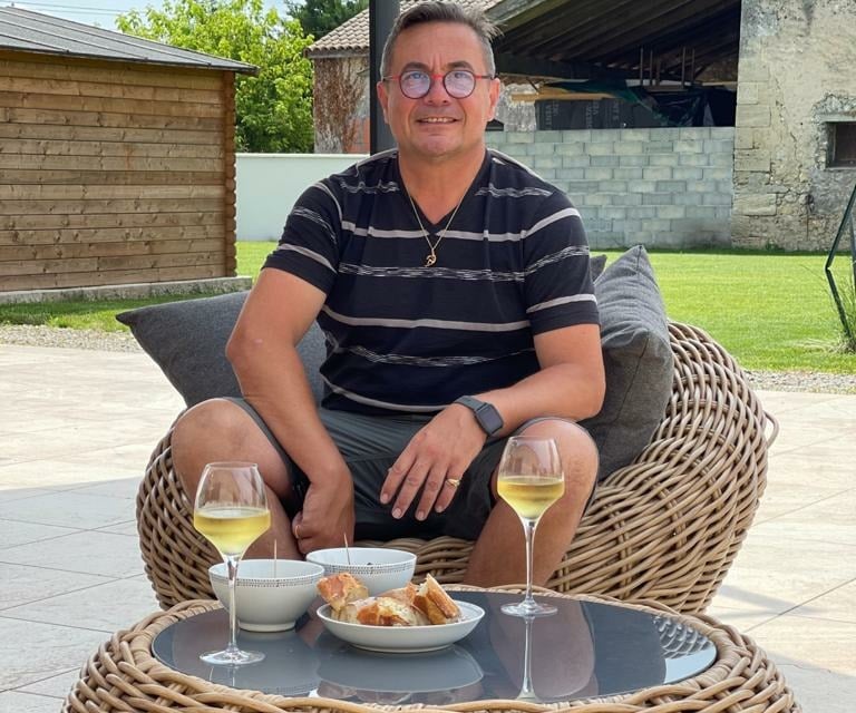 a man sitting on a wicker chair with a glass of wine
