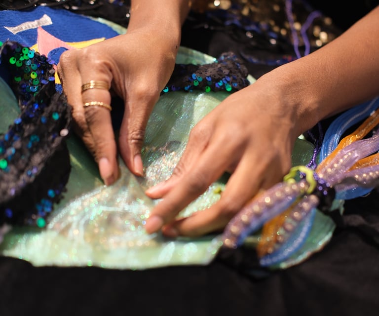 two hands play with pearls and beads inside of an imagined underwater creature made out of textiles