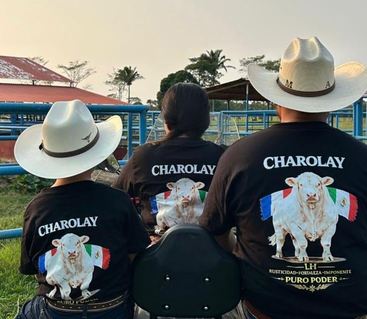 Family wearing Charolay cattle shirts and cowboy hats sitting on an ATV at a ranch.