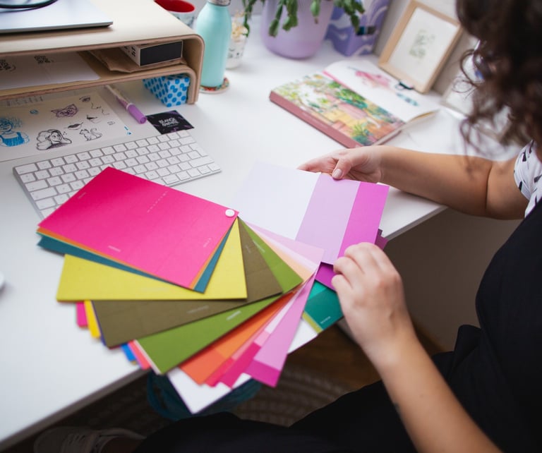 Materiales de trabajo de Blanca, incluyendo una libreta de bocetos, lápices de colores y muestras de diseño.