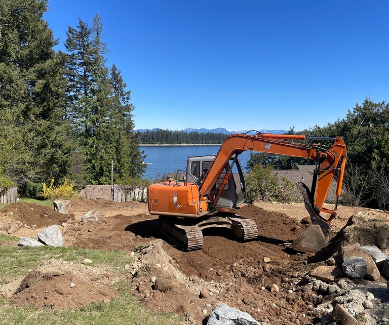 Orange heavy excavator digging a residential construction site near a lake and forest.