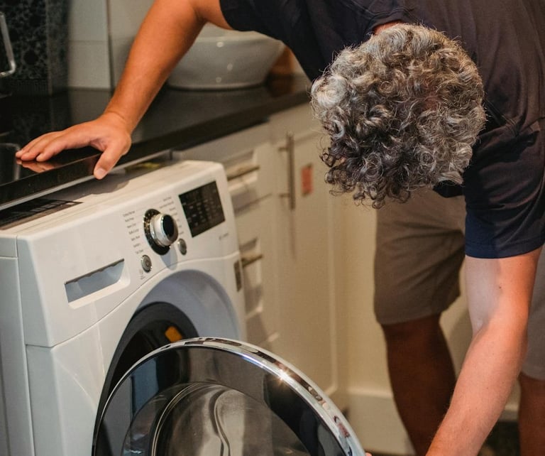 a man is standing in front of a washing machine doing laundry
