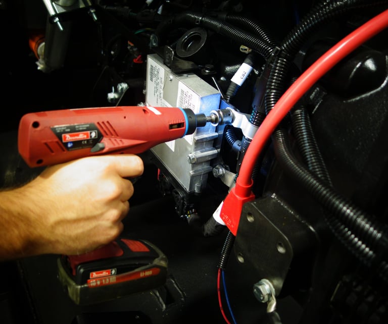 A technician uses a cordless Desoutter power tool to assemble industrial engine components.