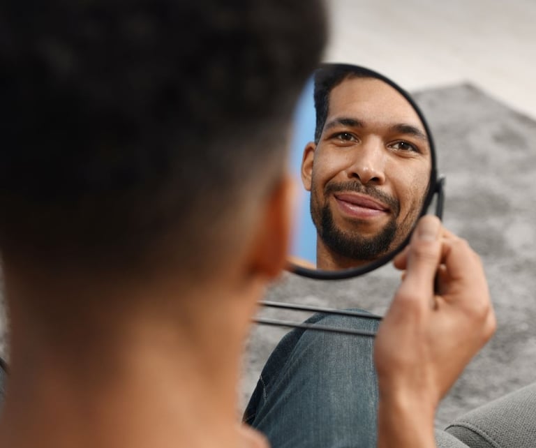 homme qui se regarde dans un miroir en souriant symbolisant apprendre à s'aimer