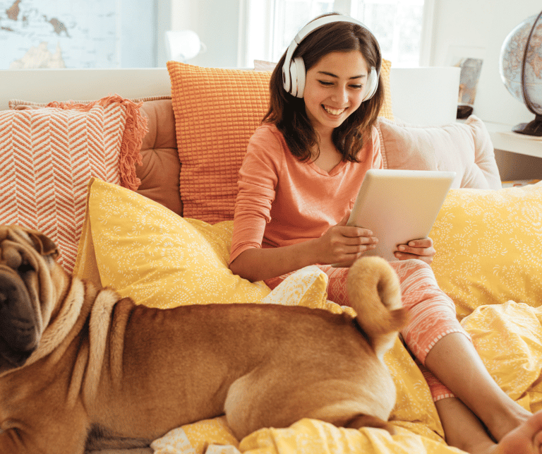 a woman sitting on a bed with a dog and a laptop