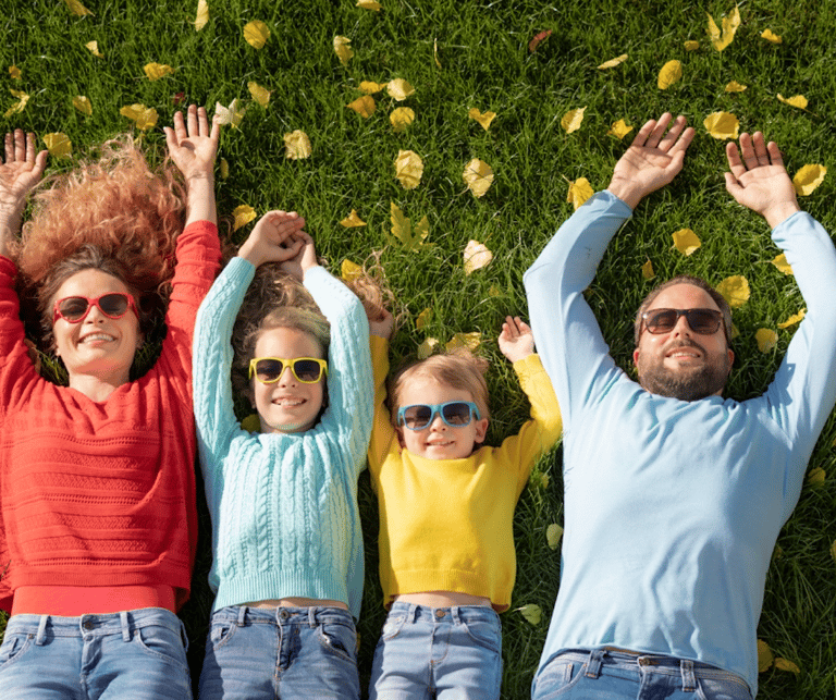 une famille heureuse, deux parents et deux enfants allongés dans l'herbe avec des lunettes de soleil