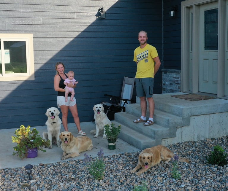 A family with their 4 dogs in front of a house