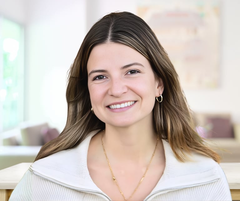 Smiling woman with brown hair wearing a white sweater and gold jewelry in a bright professional headshot.