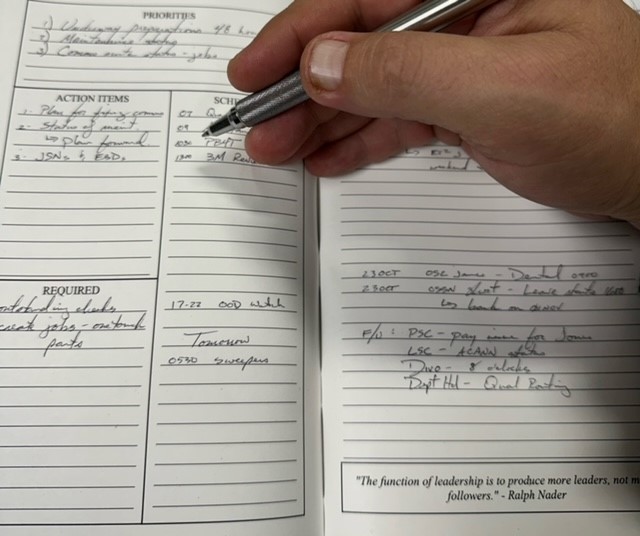 a person holding a pen and writing on a notebook