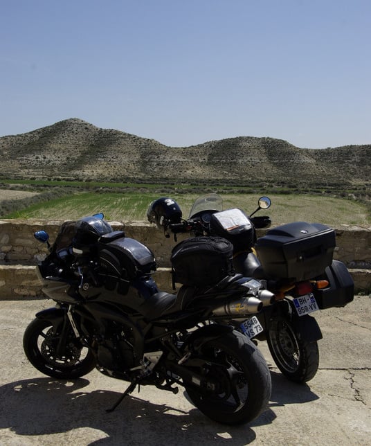 a motorcycle parked on a concrete surface with a mountain in the background