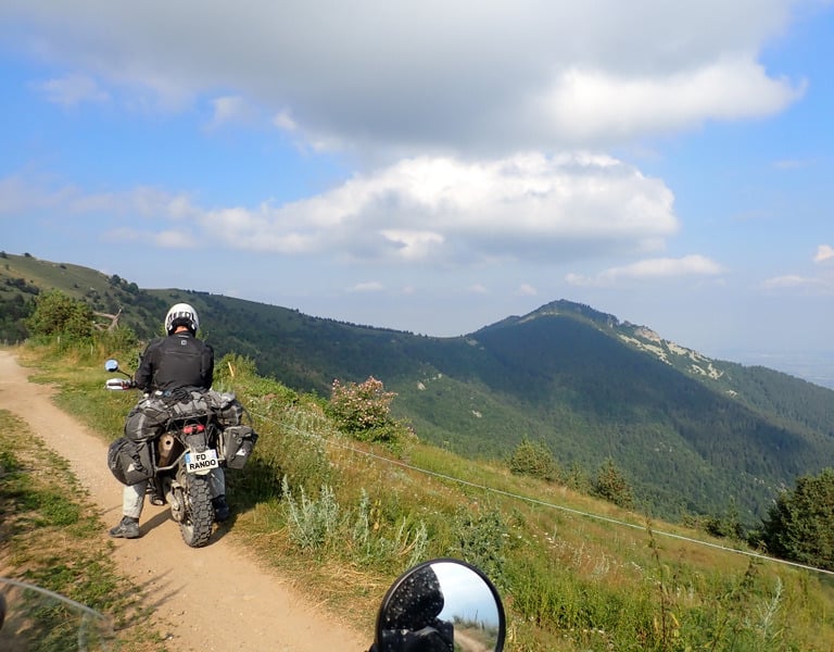 a person riding a motorcycle on a alpin dirt road