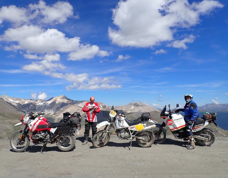 a group of motorcyclists standing in front of a mountain