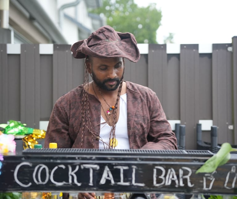 Professional bartender in a pirate costume serving drinks at an outdoor tropical cocktail bar.
