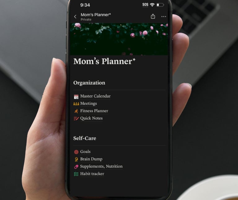 A person holding a smartphone displaying a digital Mom's Planner app with organization and self-care schedules.