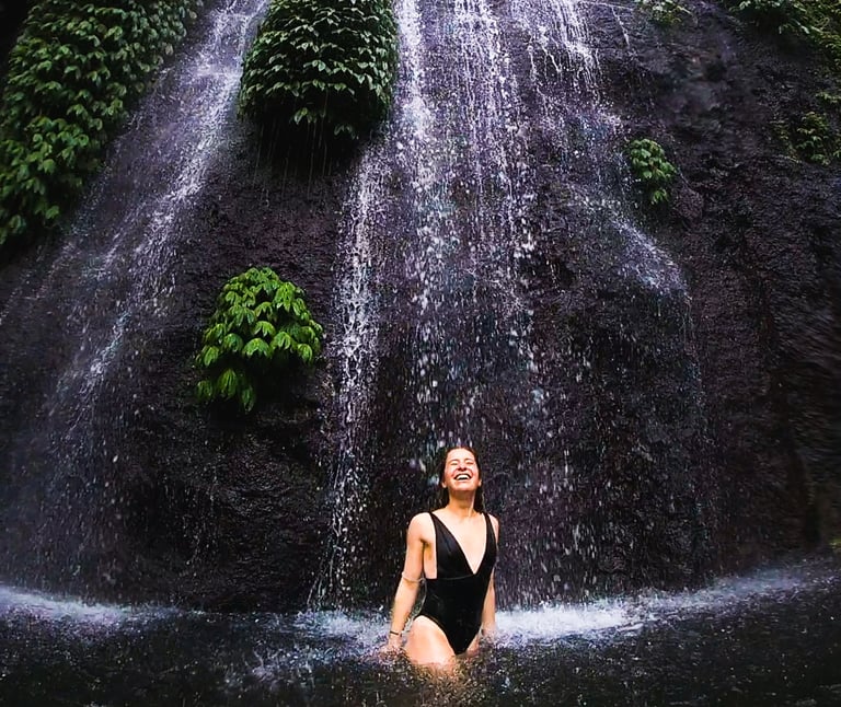 Mack Audino standing under a cascading waterfall, showcasing adventure travel and immersive experien