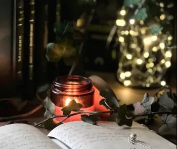 A peaceful moment showing a person writing questions to bible answers in a journal beside a candle.