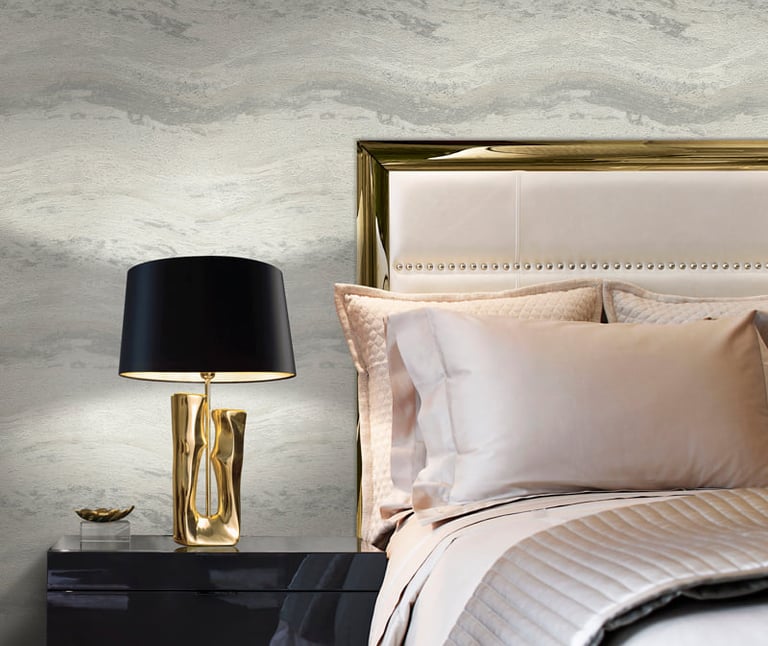 Luxury bedroom with grey marble wallpaper, gold headboard, and black designer bedside lamp.