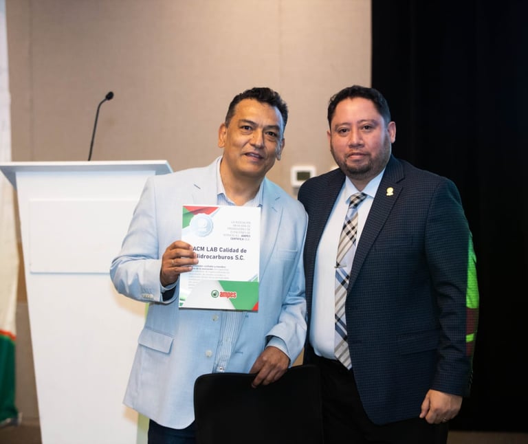 Two professional men holding an ACM LAB Calidad de Hidrocarburos certificate at an AMPES event.