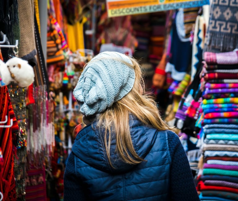 a woman in a blue jacket in a colorful market in Cusco Peru