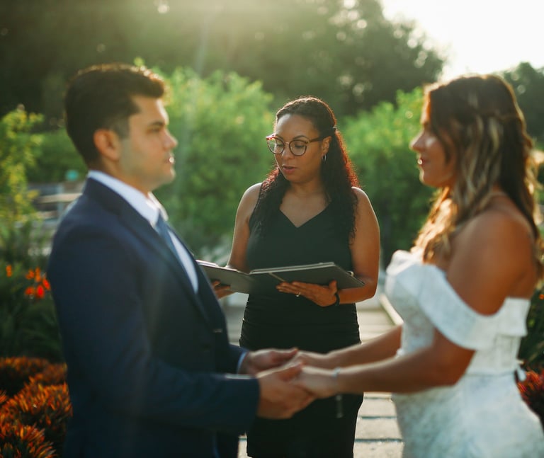 Wedding officiant performing a garden ceremony for a bride and groom during golden hour.