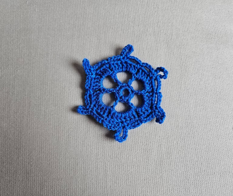 blue crochet snowflake on a light grey background