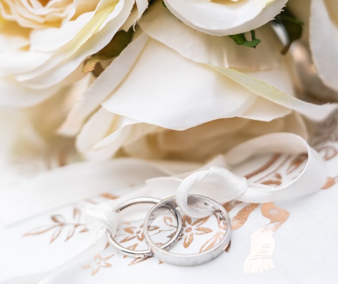 a bouquet of white roses and wedding rings