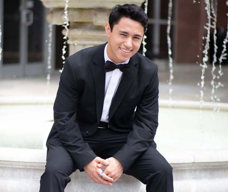 Sonny Velasco in a suit sitting on a fountain