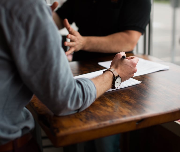 two people talking paper and pen on table