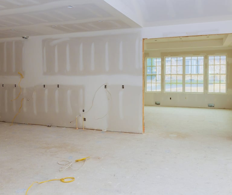 alt="Room under renovation with new drywall and windows after fire damage repair"
