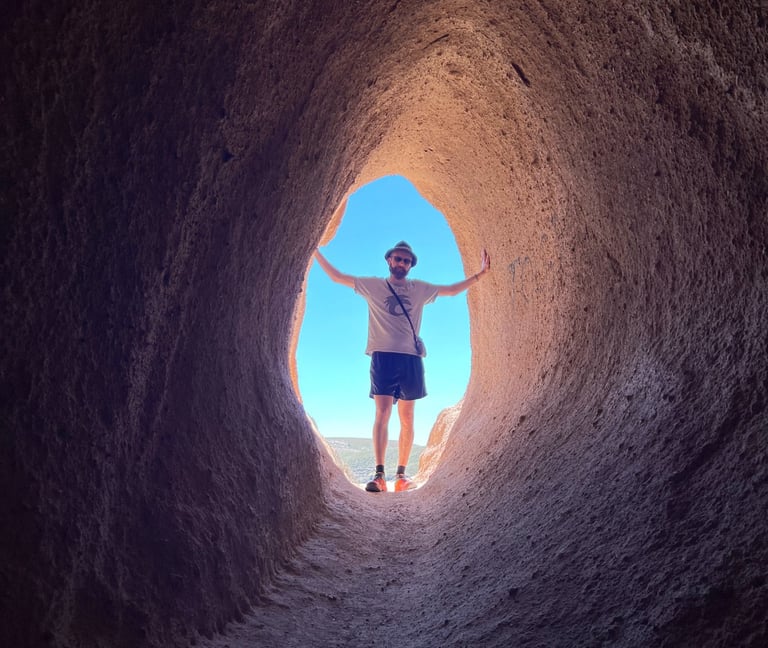 A man stands at the end of a tunnel leading to light