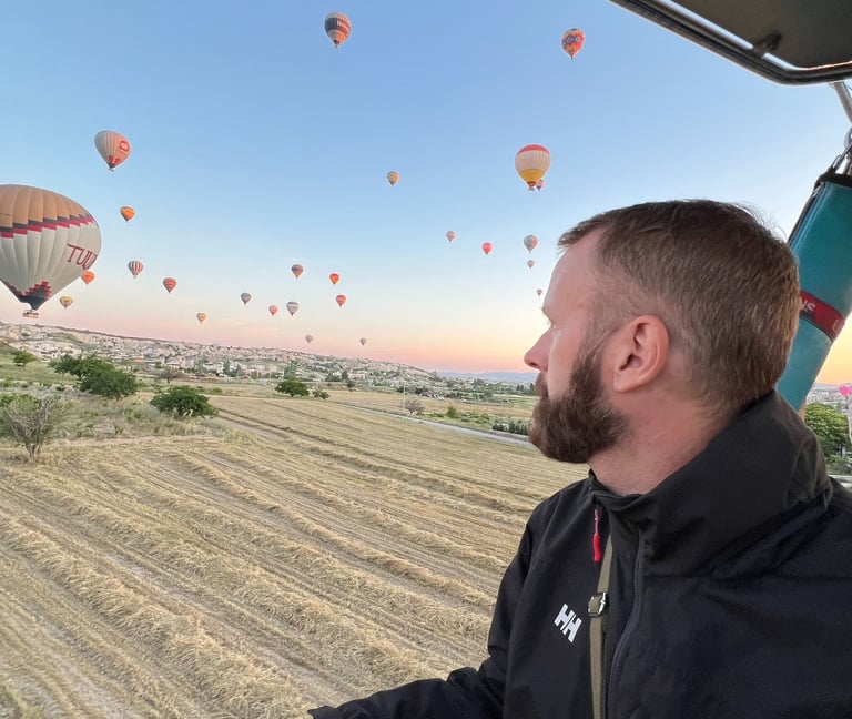 Man views the natural beauty of Cappadocia landscape from hot air balloon whilst watching sunrise